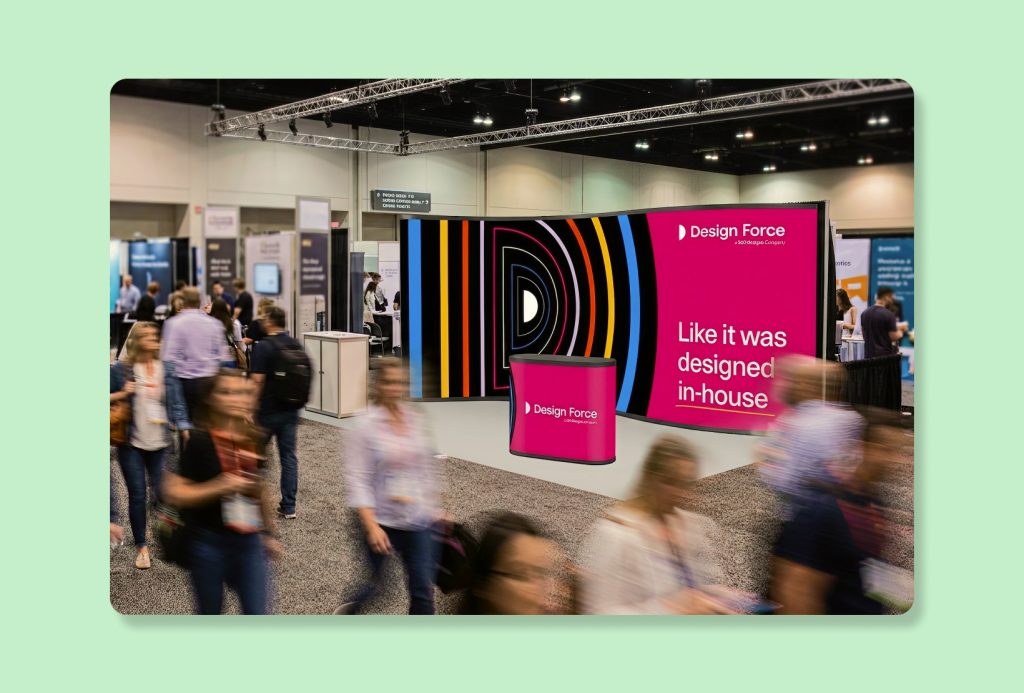 Design Force trade show booth with colorful wall graphics and attendees walking through the exhibition hall